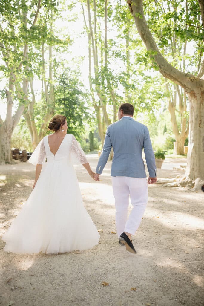 Les mariés marchant dans l’allée ombragée du domaine.